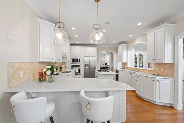 kitchen with kitchen peninsula, a breakfast bar, white cabinetry, pendant lighting, and stainless steel appliances