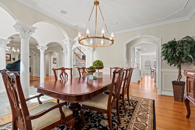 dining room with crown molding, light hardwood / wood-style flooring, and ornate columns