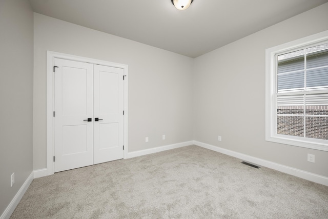 unfurnished bedroom with light colored carpet and a closet