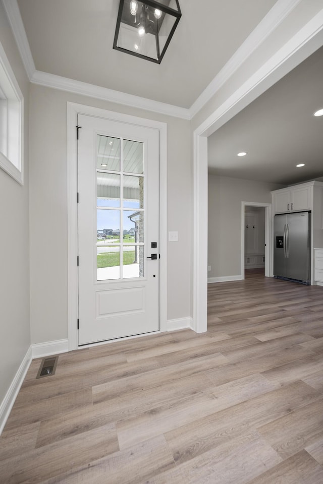 entryway with ornamental molding and light hardwood / wood-style flooring