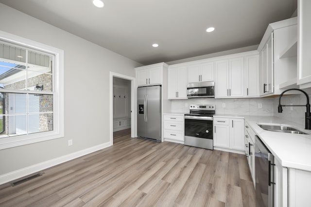 kitchen with white cabinetry, stainless steel appliances, sink, and tasteful backsplash