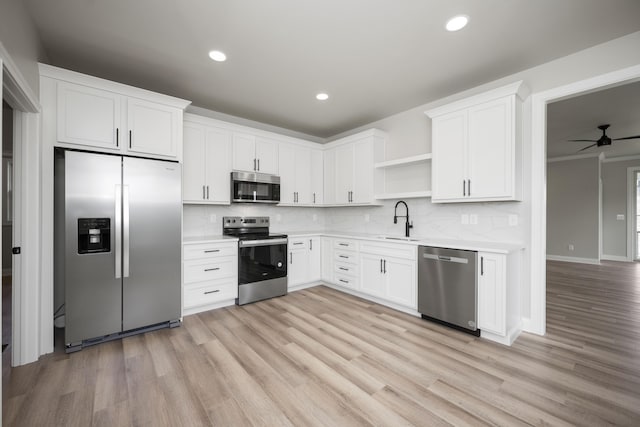 kitchen with stainless steel appliances, white cabinetry, sink, and light hardwood / wood-style floors