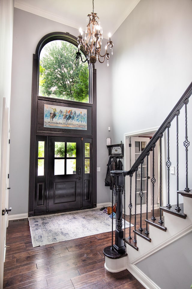 foyer featuring dark wood-type flooring, a wealth of natural light, and ornamental molding