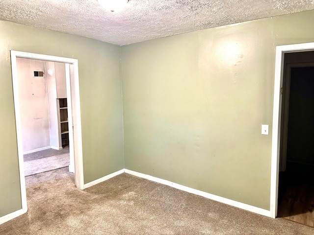 empty room with carpet floors and a textured ceiling