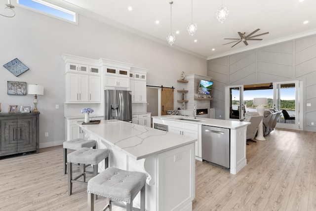 kitchen featuring pendant lighting, white cabinetry, a center island, stainless steel appliances, and a barn door