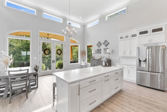 kitchen with a high ceiling, light wood-type flooring, a wealth of natural light, and refrigerator