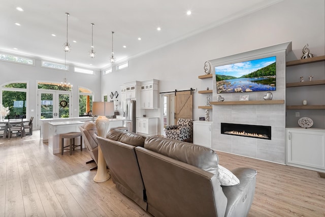 living room featuring a high ceiling, a barn door, light wood-type flooring, and french doors