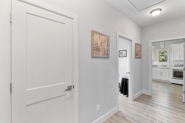 hallway featuring washer / dryer, sink, and light wood-type flooring