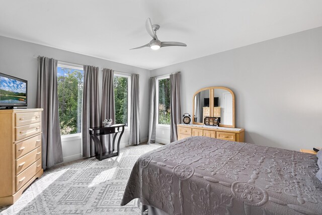 bedroom with light carpet, multiple windows, and ceiling fan