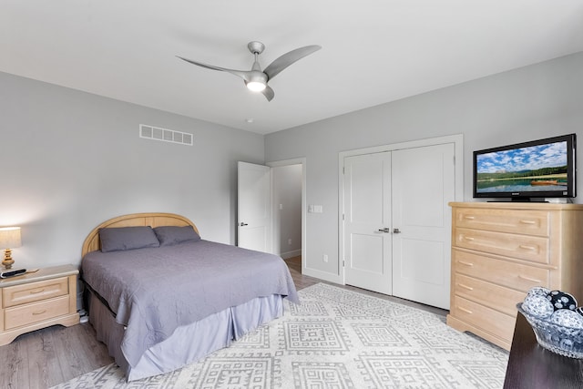 bedroom with ceiling fan, light hardwood / wood-style floors, and a closet