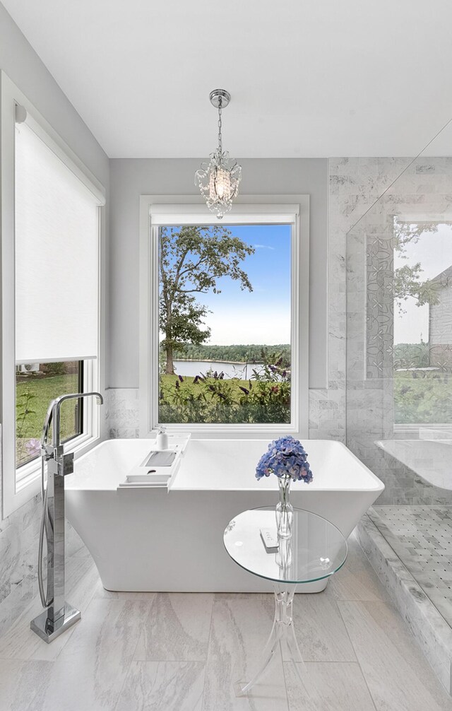 bathroom featuring a notable chandelier, a washtub, and tile patterned flooring