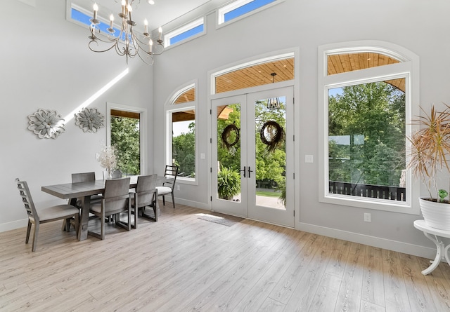 sunroom featuring a healthy amount of sunlight, a notable chandelier, and french doors