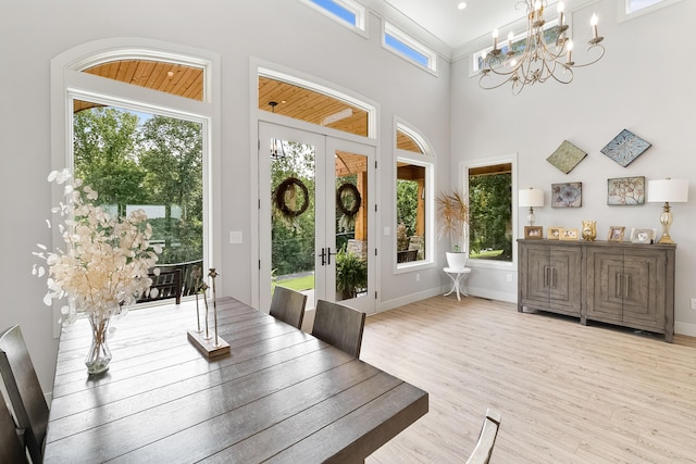 interior space with an inviting chandelier, light hardwood / wood-style flooring, french doors, and a high ceiling