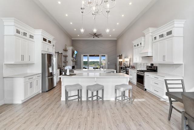 kitchen featuring white cabinetry, appliances with stainless steel finishes, an island with sink, and hanging light fixtures