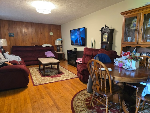 dining room featuring wood walls, a textured ceiling, and light wood-type flooring