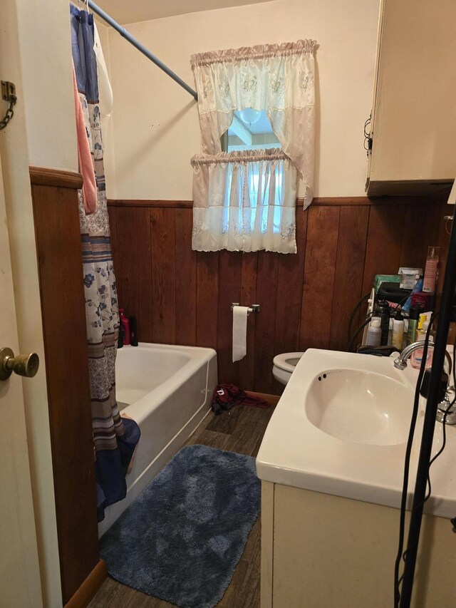 full bathroom with vanity, shower / bath combo with shower curtain, wooden walls, and toilet