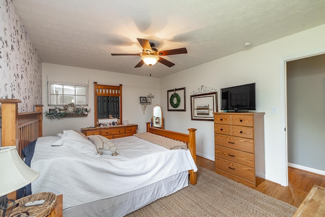 bedroom featuring a textured ceiling, wood finished floors, a ceiling fan, and baseboards