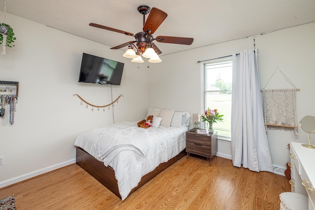 bedroom featuring light wood-type flooring, multiple windows, ceiling fan, and baseboards