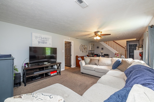 living room featuring carpet, visible vents, stairway, ceiling fan, and a textured ceiling