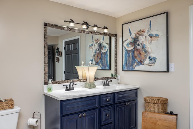 bathroom with toilet, double vanity, and a sink