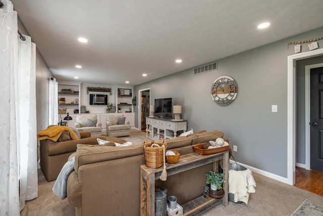 carpeted living area featuring built in shelves, recessed lighting, visible vents, and baseboards