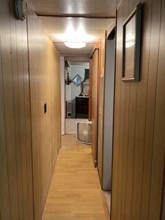 corridor featuring light wood-style flooring and wooden walls