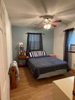 bedroom with ceiling fan, cooling unit, and wood-type flooring