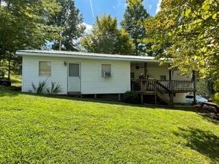 rear view of property with a wooden deck and a lawn