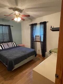 bedroom with ceiling fan, cooling unit, and hardwood / wood-style flooring