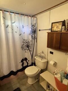 full bathroom with toilet and a shower with shower curtain