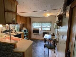 kitchen featuring dark tile patterned flooring, stove, kitchen peninsula, and decorative backsplash