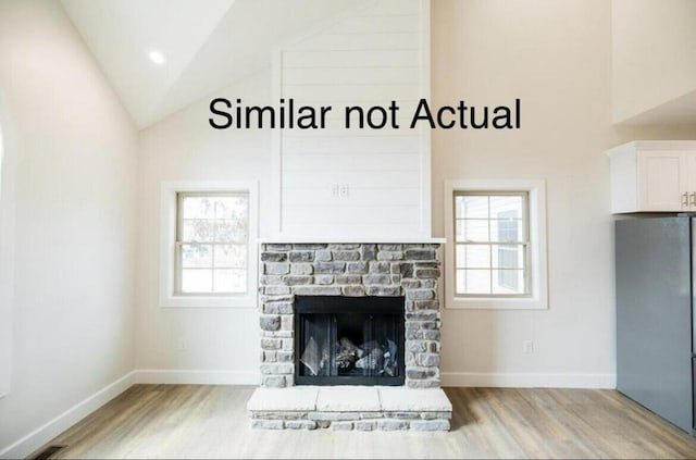 unfurnished living room featuring light wood-type flooring, a fireplace, and high vaulted ceiling