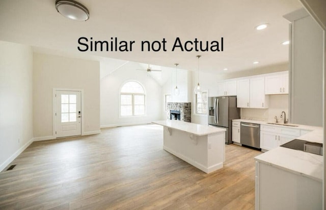 kitchen featuring white cabinetry, a fireplace, light hardwood / wood-style flooring, appliances with stainless steel finishes, and decorative light fixtures