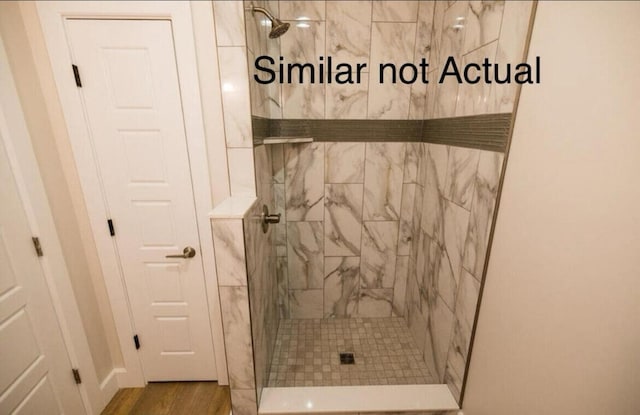 bathroom featuring hardwood / wood-style flooring and a tile shower