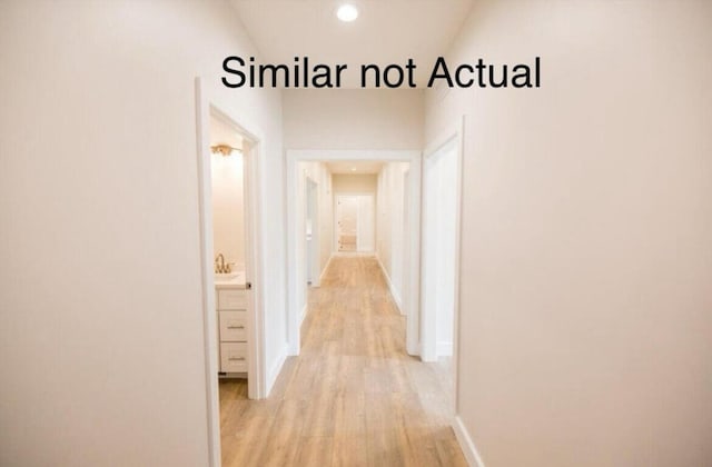 corridor with light hardwood / wood-style floors and lofted ceiling