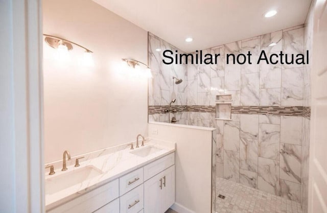 bathroom with a tile shower and vanity