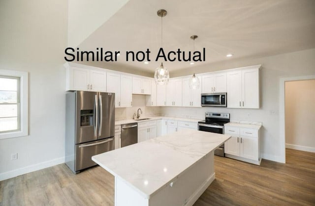 kitchen featuring white cabinetry, appliances with stainless steel finishes, decorative light fixtures, and a center island