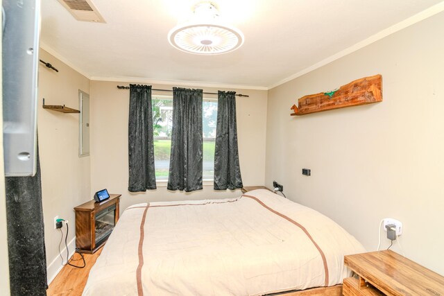 bedroom featuring ornamental molding and light wood-type flooring