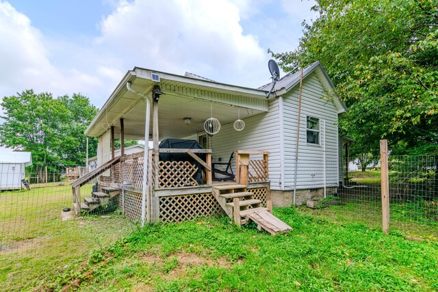 rear view of property featuring a deck and a lawn