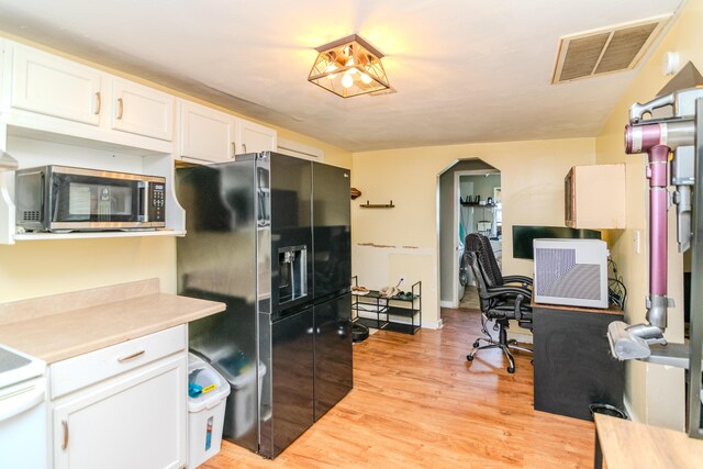 kitchen featuring black fridge, light hardwood / wood-style flooring, white cabinetry, and stove