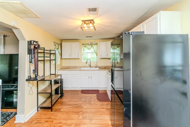 kitchen with white cabinets, stainless steel refrigerator, sink, and light hardwood / wood-style floors