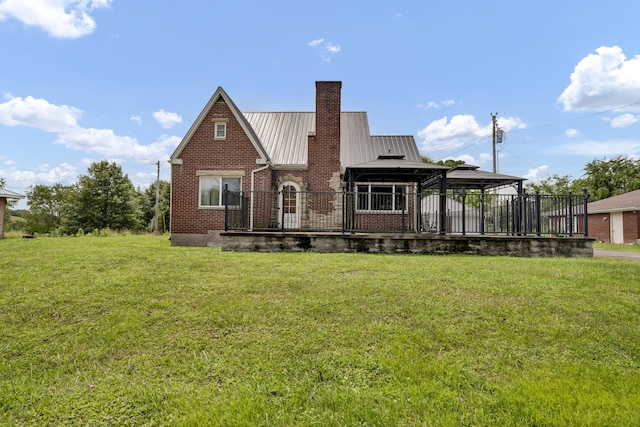 rear view of property with a gazebo, a wooden deck, and a lawn