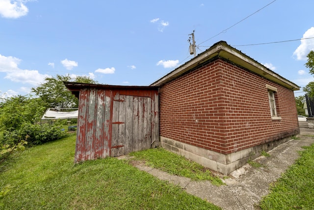 view of property exterior featuring a lawn and a storage unit