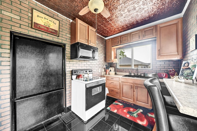 kitchen featuring sink, dark tile patterned flooring, ceiling fan, brick wall, and white range with electric stovetop