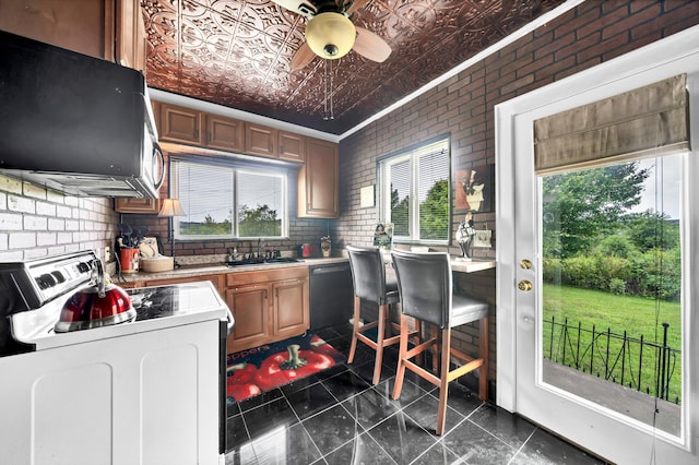 kitchen with white electric range oven, sink, ventilation hood, dishwasher, and brick wall