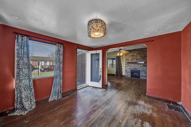 interior space featuring a stone fireplace, dark hardwood / wood-style floors, and ceiling fan