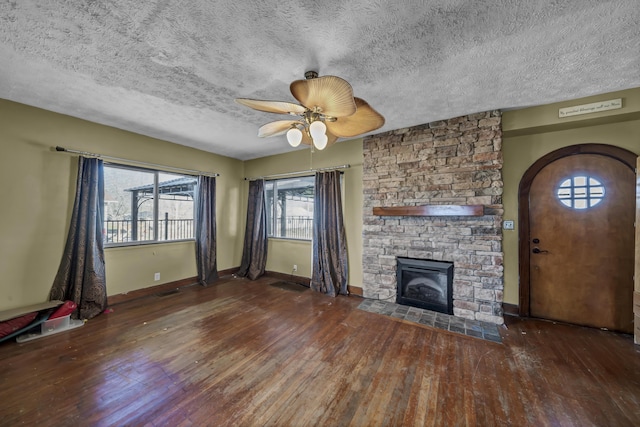 unfurnished living room featuring a textured ceiling, a fireplace, dark hardwood / wood-style floors, and ceiling fan