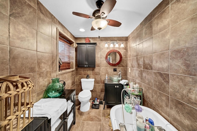 bathroom featuring tile walls, tile patterned flooring, a tub, and toilet