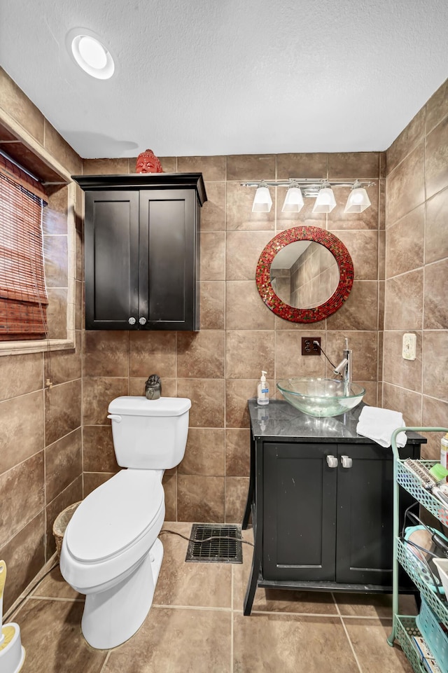 bathroom with tile walls, tile patterned flooring, vanity, a textured ceiling, and toilet