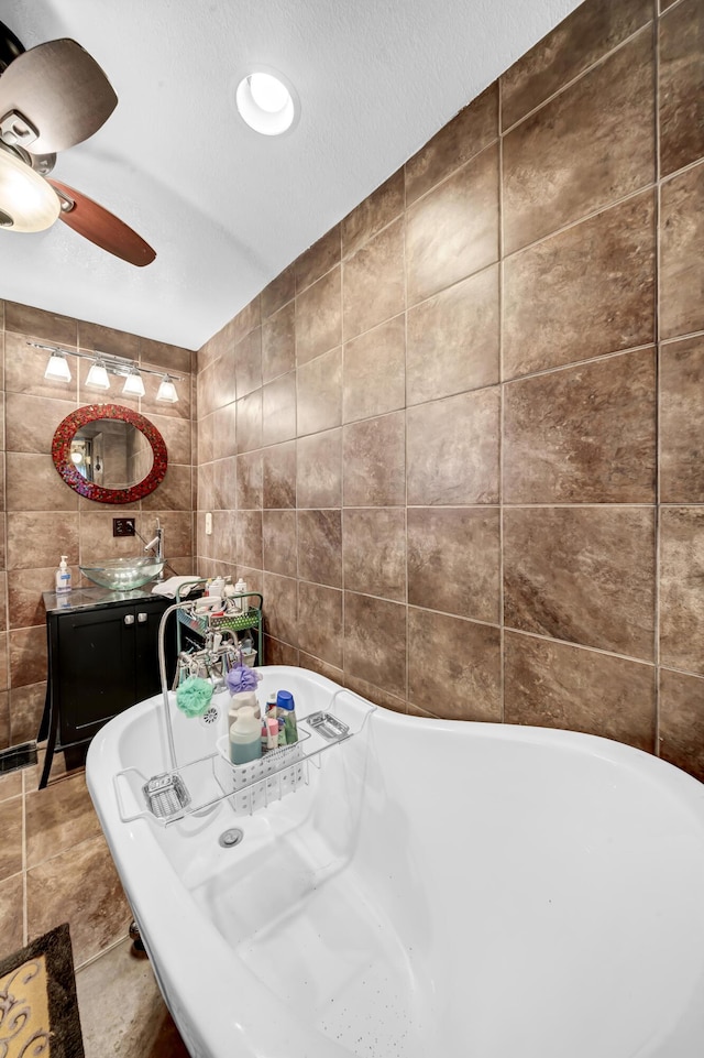 bathroom featuring tile patterned floors, sink, a textured ceiling, tile walls, and a washtub